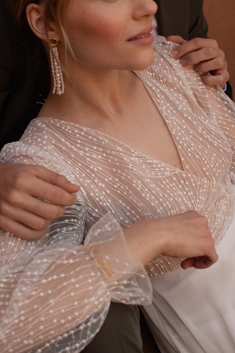 Pétunia is a charming beauty! The chiffon skirt has a front slit and a sweep train. The top is made of ivory embroidered tulle lined in beige, with a wrapped V neckline and keyhole open back. The long sleeves are finished with soft flounced cuffs.