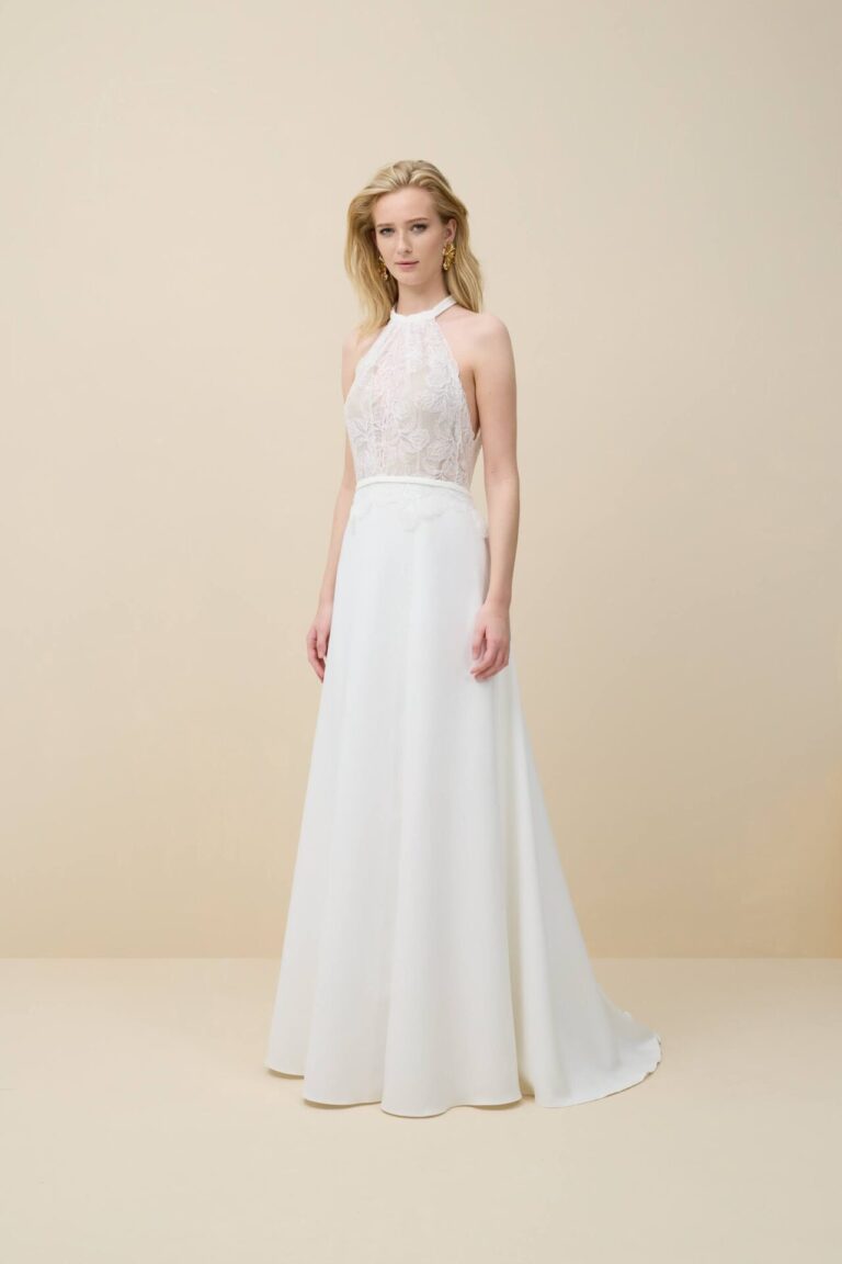 Promesse is a modern and romantic wedding dress. The top features a halter neckline of ivory lace that touches the skirt. A detachable crepe scarf completes the look. The crepe skirt has an A-line fit and a train.